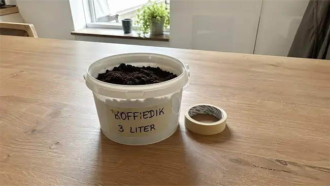 Oesterzwammen kweken op koffiedik in een witte emmer op een houten keukentafel