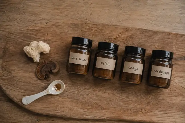 Adaptogene paddenstoelen supplementen Lion's Mane Reishi Chaga en Cordyceps op houten plank