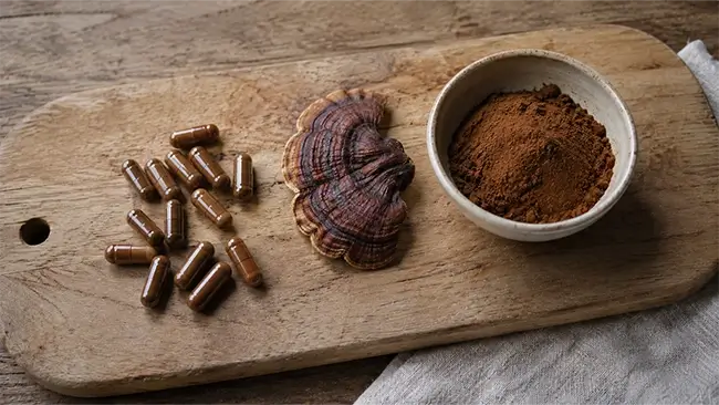 Reishi capsules en poeder op een houten plank